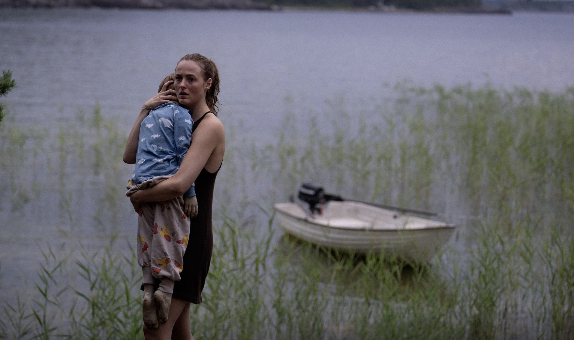 En liten båt med en mor vid vattnet som håller om sitt barn