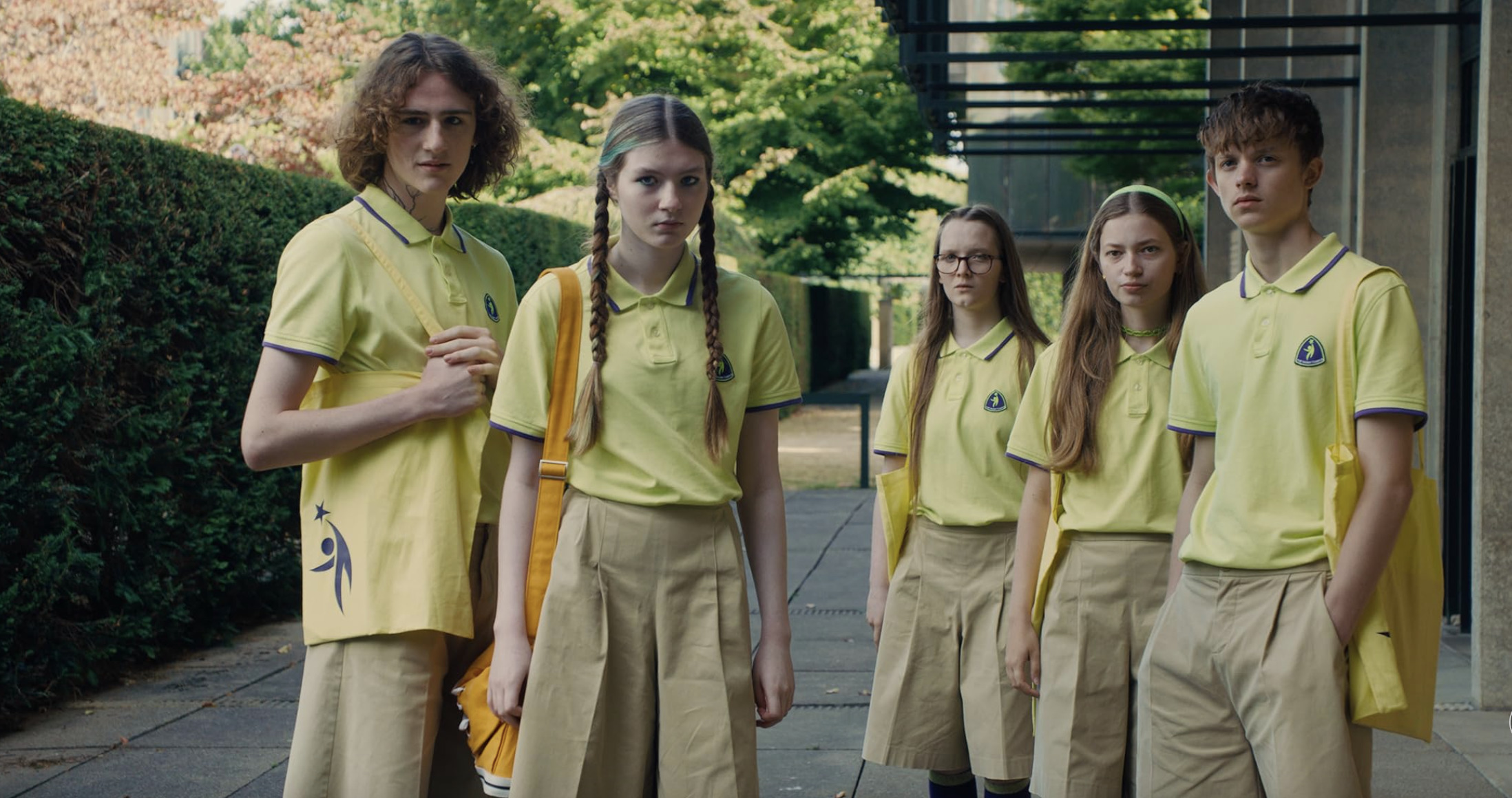En grupp elever i gula pikétröjor och beige kortbyxor eller kjolar